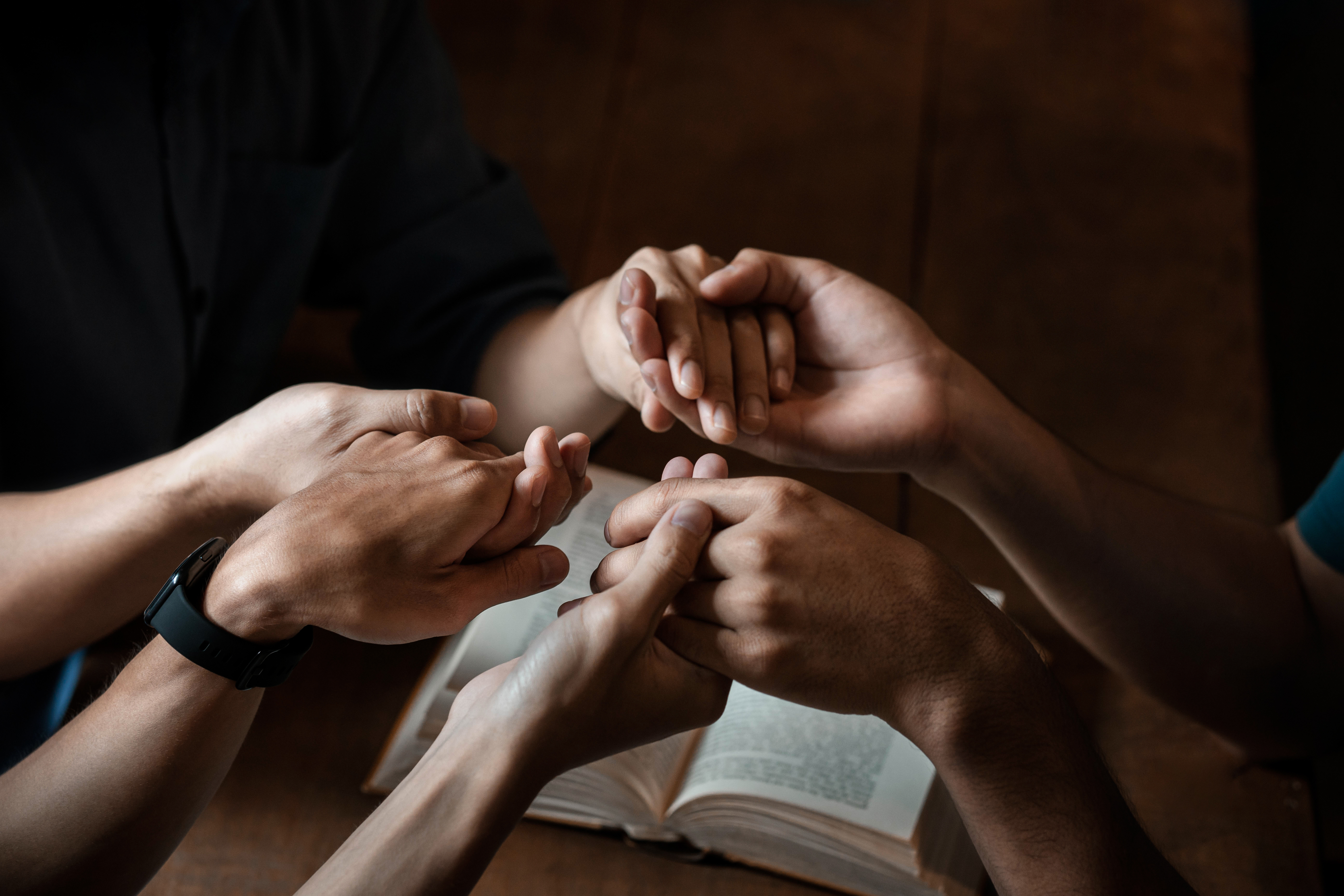 A group of young Christians holding hands in prayer for faith an